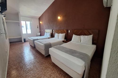 a hotel room with two beds in a room at Capital O Hotel Rolovi Cancún in Cancún