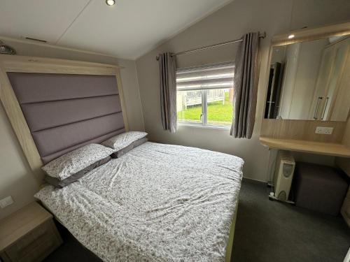 a bedroom with a bed and a mirror and a window at Poplars 33, 3 Bedroom Luxury Caravan Trecco Bay Porthcawl in Porthcawl