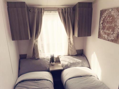 two beds in a small room with a window at The Retreat Gold - Lido Beach Prestatyn in Prestatyn