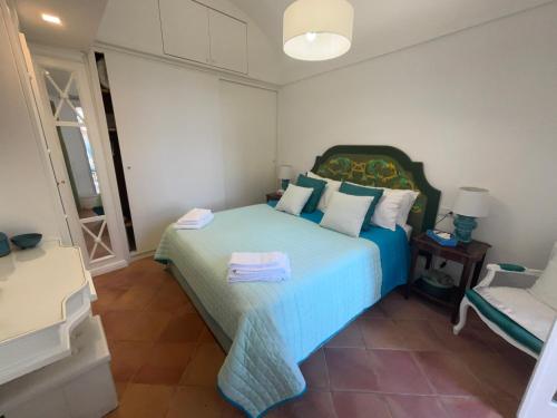 a bedroom with a blue bed and a chair at EXCLUSIVE LUXURY HOUSE "VILLA POMPEIANA" IN VIA CAMERELLE 65a CON TERRAZZA VISTA MARE in Capri