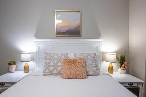 a white bedroom with a white bed with two lamps at Lots of Hot Spots & Activities Near This Townhome in Cartersville