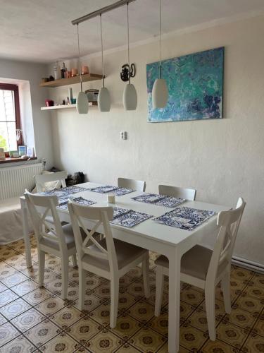 a white dining room table with white chairs and a painting at Cat’s House- Dům u třech koček in Zdice