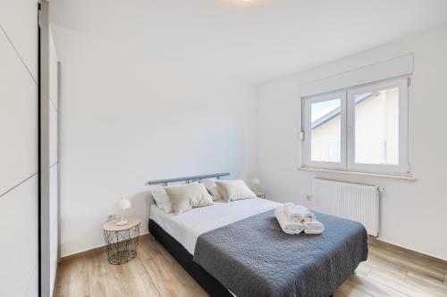 a white bedroom with a bed and a window at Vila Baruni in Sukošan