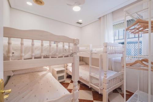 zwei weiße Etagenbetten in einem Zimmer mit Fenster in der Unterkunft El Pez Volador by Gades Gestión in Cádiz
