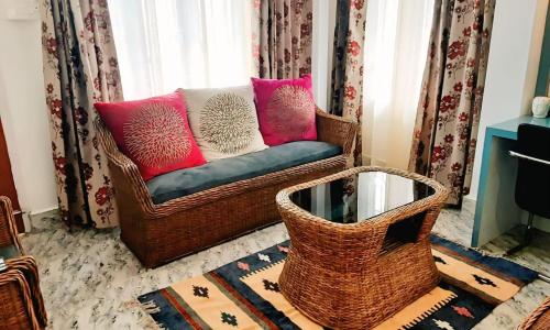 a wicker couch with pink and white pillows in a living room at Tranquil Trails Homestay in Guwahati
