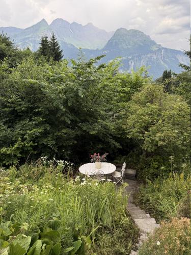 a table and chairs in a garden with mountains in the background at Chalet Montana mit Bergblick in Brunig