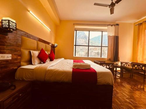 a bedroom with a bed with red pillows and a window at WooibHotels The Kalinga Grand Manali in Manāli