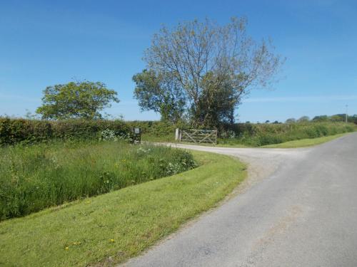 a dirt road with a gate on the side of a field at The Barn At Collacott in North Petherwin