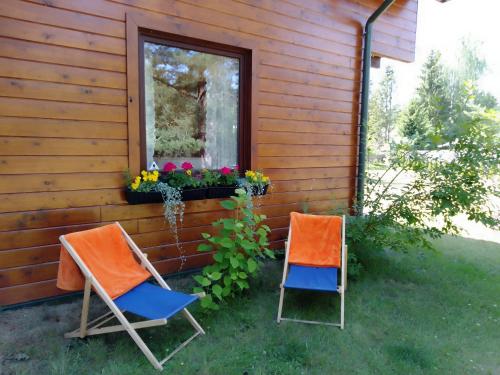 two chairs sitting outside of a house with a window at 7 NIEBO Ewa Olechno in Nowinka