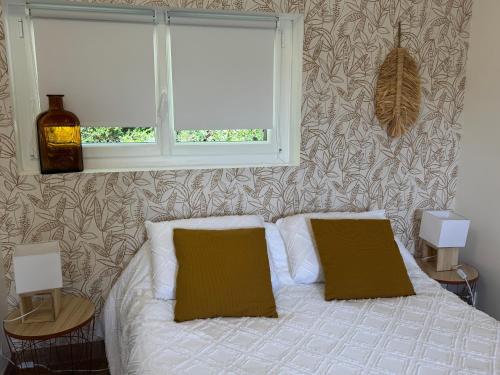 Un dormitorio con una cama con dos almohadas y una ventana. en Studio proche Aéroport de Nantes, en Saint-Aignan-Grand-Lieu