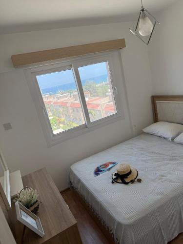 a bedroom with a bed and a window with a hat on it at Two Bedrooms LongBeach SeaView Escape in Paralimni