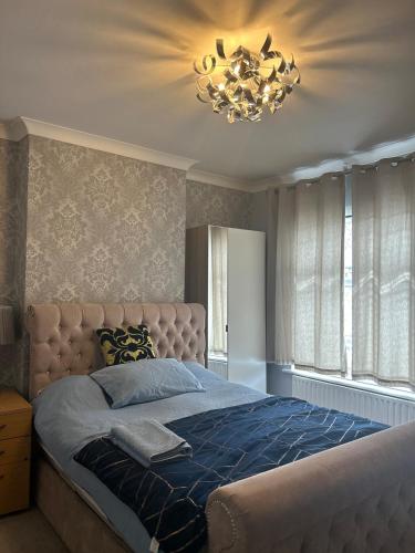 a bedroom with a large bed and a chandelier at Narie Little Cottage in Brierley Hill