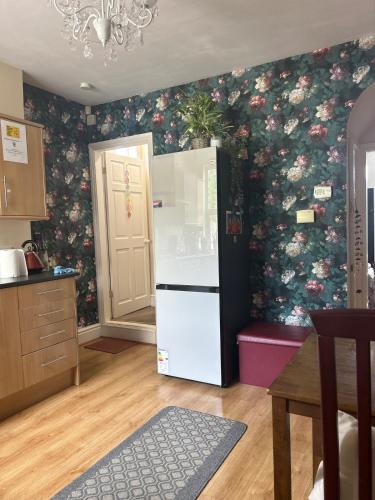 a kitchen with a refrigerator with a floral wallpaper at Narie Little Cottage in Brierley Hill
