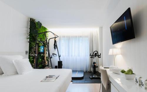 a white room with a bed and a tv on the wall at Hotel Zentral Castellana Norte in Madrid