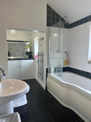 a bathroom with a white tub and a sink at Narie Little Cottage in Brierley Hill