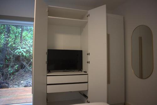 a living room with a tv and a cabinet at White Haus 2 - Rainforest heaven close to beaches in Ucluelet
