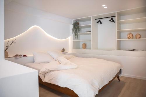 a white bedroom with a large bed with white sheets at Gastenverblijf Stationskoffiehuis - Perron 1 in Ravenstein
