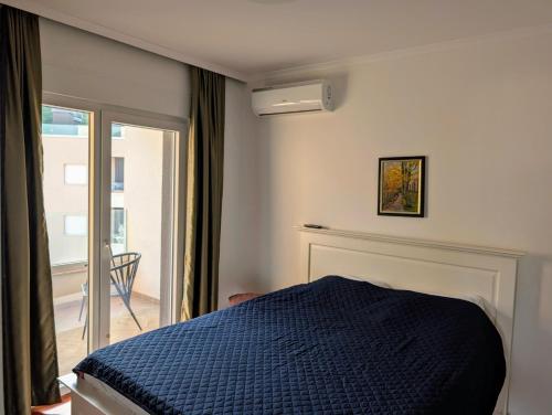 a bedroom with a blue bed and a balcony at Penthouse NIKOLA in Budva