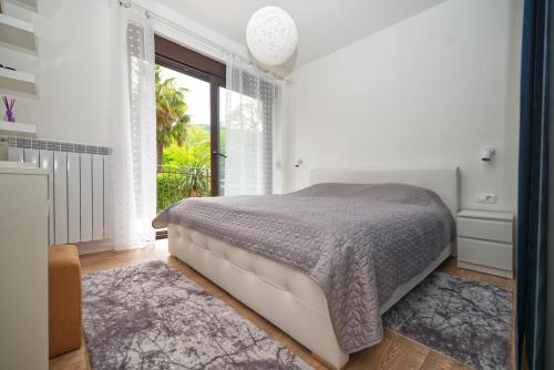 a bedroom with a bed and a large window at Apartman Sara in Dražice