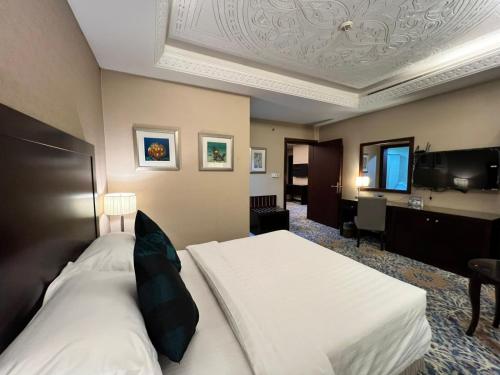 a hotel room with a bed and a television at Merkure Jeddah Al Hamraa Hotel in Jeddah