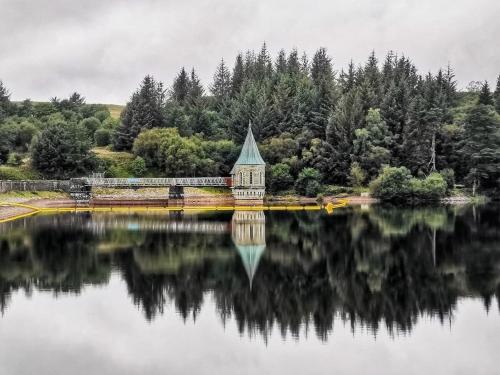 a building sitting on the edge of a lake at 4 - Walkers Cottage - Scandinavian BBQ hut -Open fire in Pont Sticill