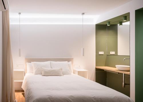 a bedroom with a white bed and a sink at La Pata Suites in Trujillo