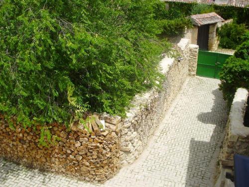 a stone wall next to a tree and a sidewalk at Casa los Tres Nogales in Castroserna de Arriba