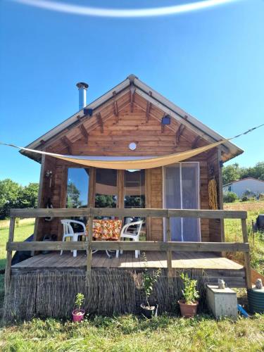 a log cabin with a porch and chairs in the grass at La casita in Villefranque