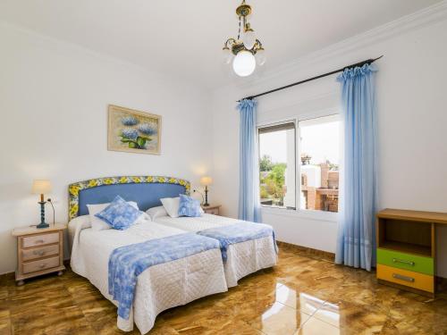 ein Schlafzimmer mit einem Bett mit blauen Vorhängen und einem Fenster in der Unterkunft Cubo's Villa San Jose in Alhaurín el Grande