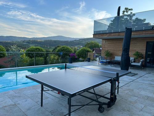 a ping pong table on a patio next to a pool at Traumhaus in den Weinbergen - max 8 Personen - mit Self-Check-in in Sankt Stefan ob Stainz