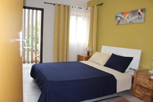 a bedroom with a blue and white bed and a window at Appartement BIKA à 5 mn de l'aéroport d'Ivato - navette privée gratuite in Talata-maty