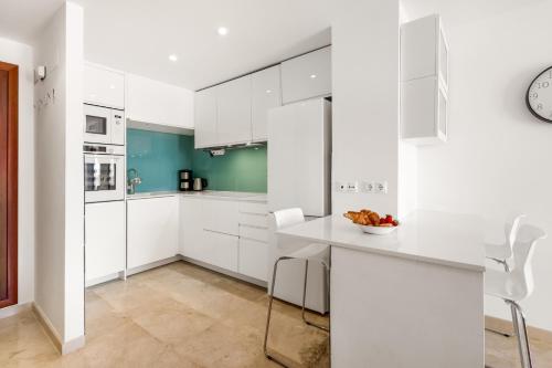 a white kitchen with white cabinets and a counter at Apartment Holiday Haven in Punta Prima