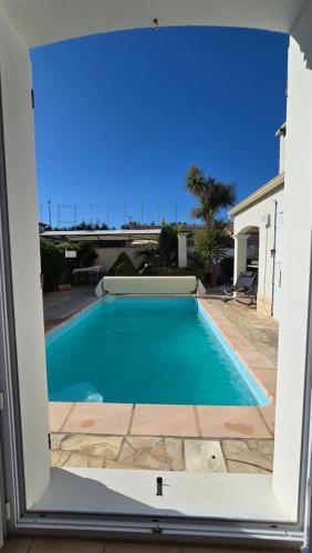 a view of a swimming pool through a window at Lieblingshaus mit beheizten Privatpool und Ladesäule in Portiragnes