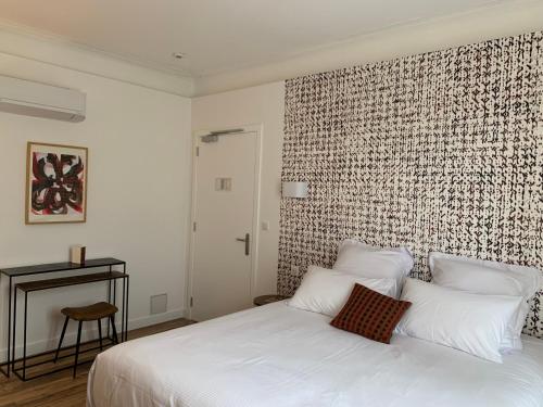 a bedroom with a white bed with a brick wall at Hotel Restaurant O'Banel in Gallargues-Le-Montueux