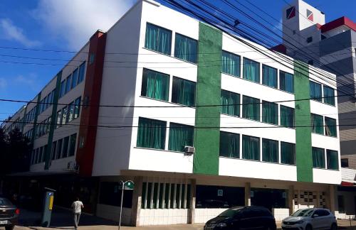 a white and green building with cars parked in front of it at Apartamento na Praia do Forte - Cabo Frio in Cabo Frio