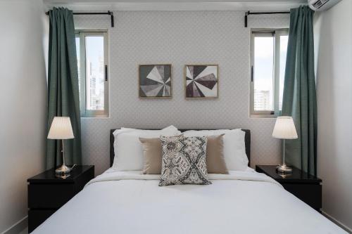 a bedroom with a large white bed with two lamps at JR 7 Suites by Yellowkey in Santo Domingo