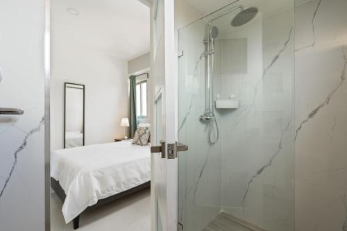 a white bathroom with a shower and a bed at JR 7 Suites by Yellowkey in Santo Domingo