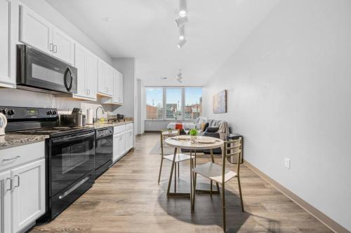 a kitchen with white cabinets and a table with chairs at MDRN Escape with Natural Light Wi-Fi Gym Parking in Cleveland