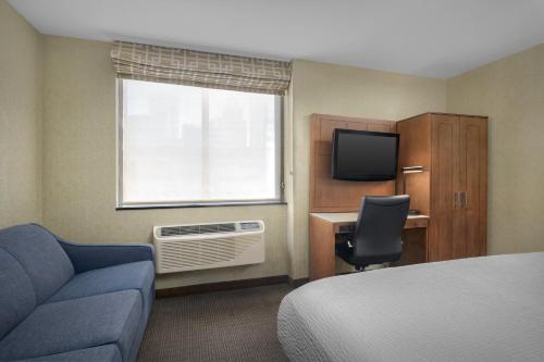 a hotel room with a bed and a desk and a television at Holiday Inn Express Manhattan Midtown West by IHG in New York