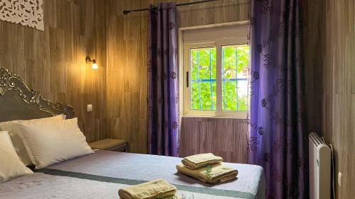 a bedroom with a bed with purple curtains and a window at Imperio de Memorias - Casa de Campo in Vale Bordalo