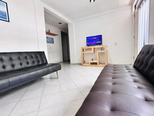 a living room with two leather couches and a tv at Suite#11 Cerca de Auto. Mex-Qro. in Cuautitlán Izcalli