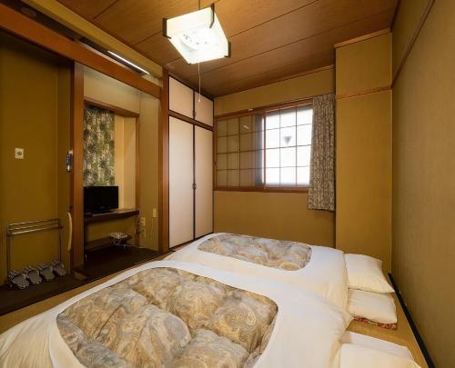 a large bed in a room with a window at Business Hotel Nakayama in Nagoya