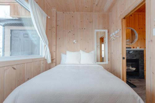 a bedroom with a large bed and a window at Le Hélios - MicroChalet au Maelstrom in Lac-Beauport
