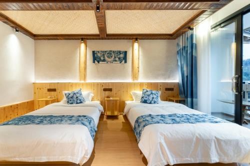 雷山县Xijiang Longtang Liyuan Mountain Resort B&B的配有窗户的客房内的两张床