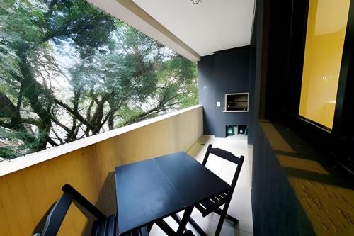 a table and chairs on a balcony with a window at Sky Batel - Apartamentos UROOMS in Curitiba