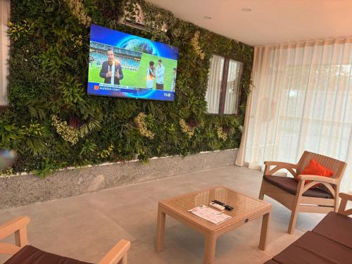 a living room with a green wall with a tv at Hotel Futuro in Aversa