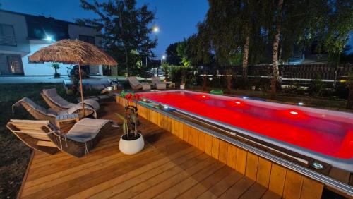a swimming pool with chairs and an umbrella on a deck at Domek Liliowe Marzenie in Chrzanów
