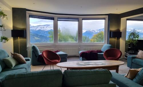 a living room with couches and a table and windows at Vermont Hub for Offsites, Retreats & Individual Bookings in Alps in Leysin