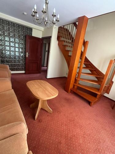 a living room with a couch and a wooden staircase at Ośrodek Wypoczynkowy Przystań Energii in Nadole