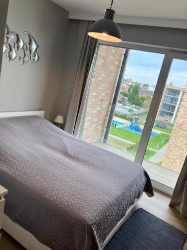 ein Schlafzimmer mit einem Bett und einem großen Fenster in der Unterkunft Apartament MioMare, Basen, Parking in Kołobrzeg